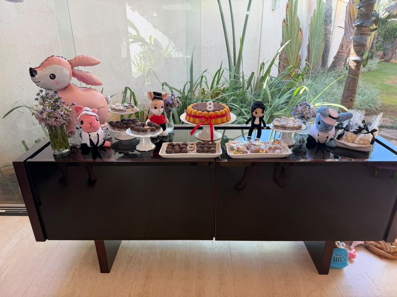 Bolo com brigadeiros e laço vermelho na mesa da festa