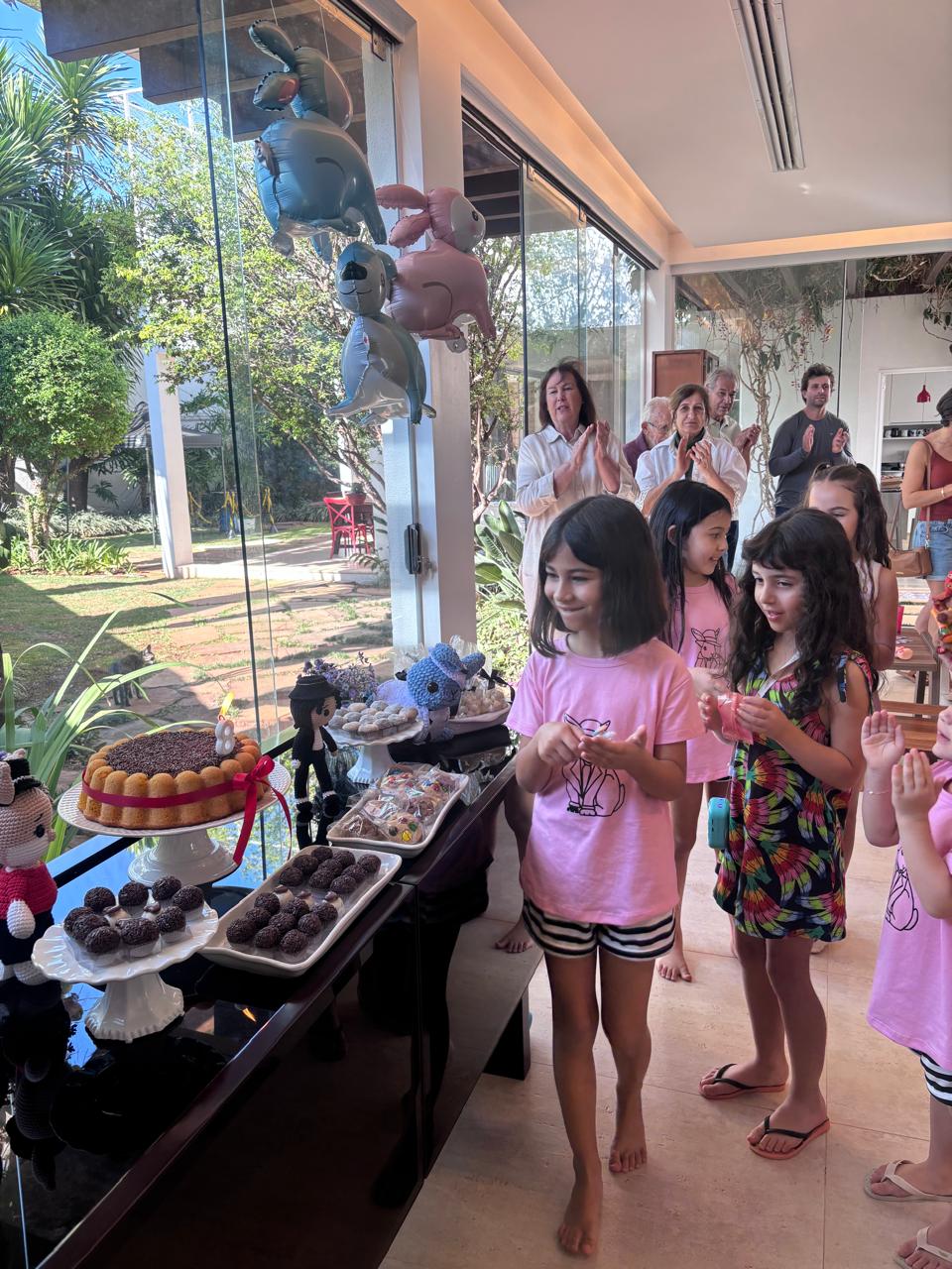 Convidados cantando parabéns ao lado da mesa de doces