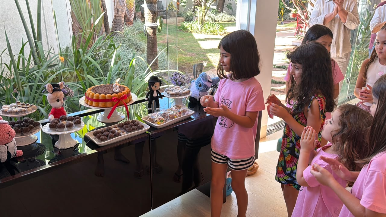 Crianças aplaudindo em frente à mesa de doces