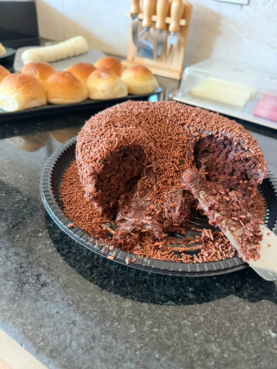 Bolo de chocolate com granulado, recheio cremoso, já fatiado