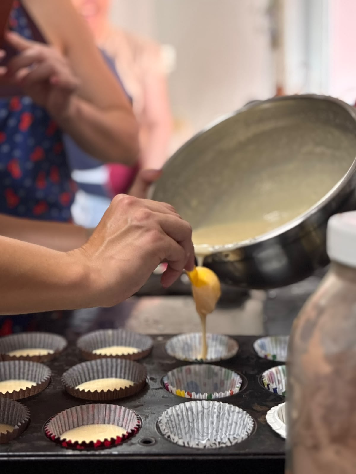 Participante colocando massa nas forminhas de cupcake