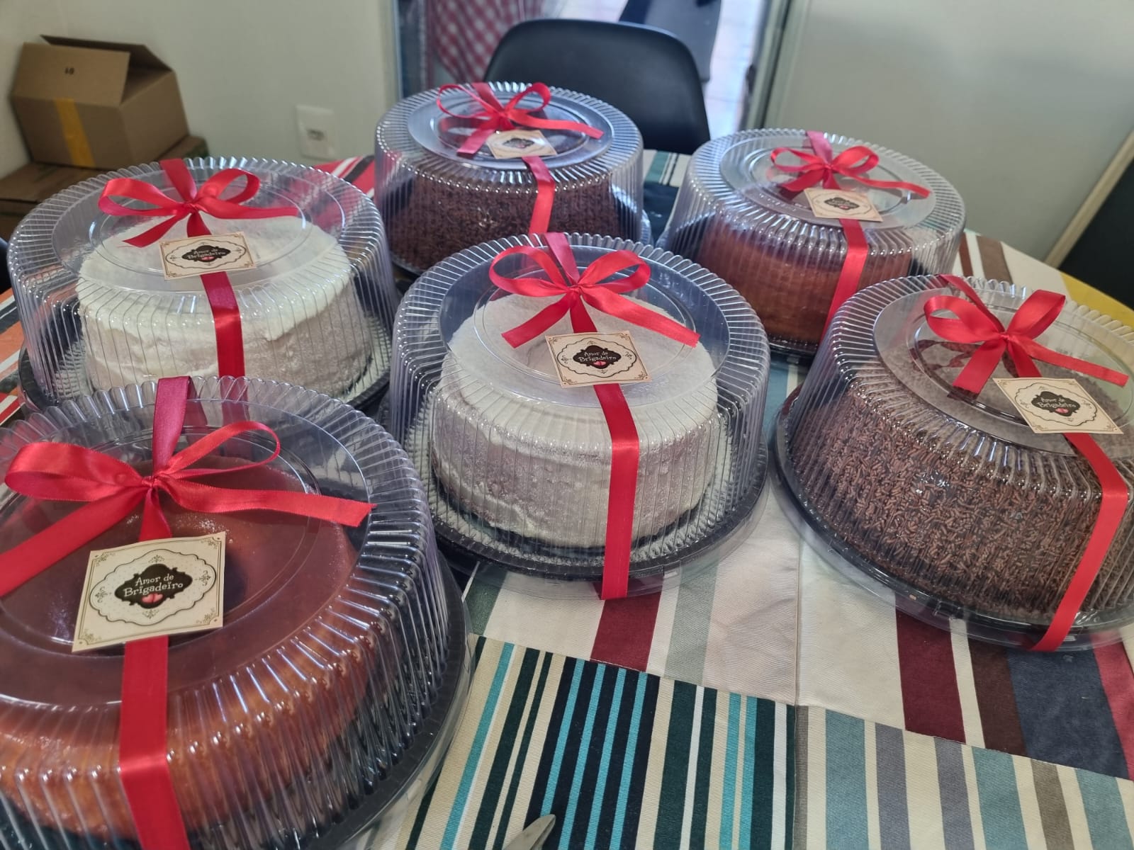 Mesa com vários bolos cobertos e embalados